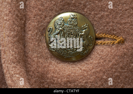 Bottone decorativo color oro con Dieu et mon droit motto E scudo dello stemma del Regno Unito Su cappotto di lana marrone Daniel Hechter Foto Stock