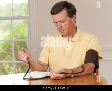 Senior caucasico maschio in pensione tenendo la pressione sanguigna a casa Foto Stock