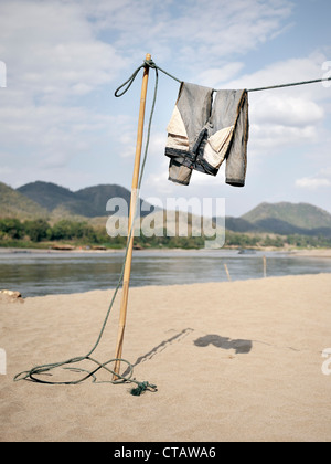 Pantaloni essiccazione su linea di lavaggio a riva del fiume Mekong, spiaggia sabbiosa, a Luang Prabang, Laos Foto Stock