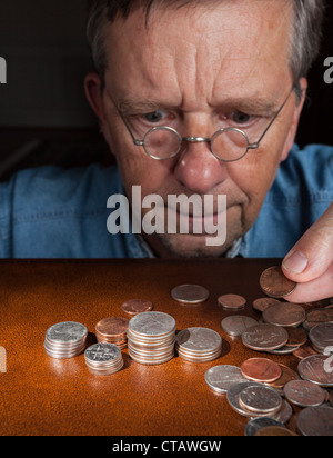 Senior pensionati uomo caucasico counting out cash in pile Foto Stock