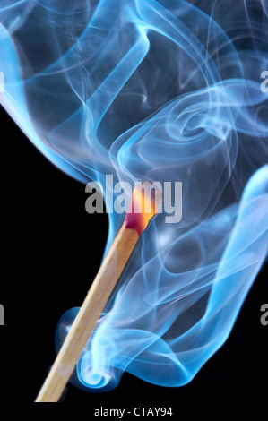 Foto di un fiammifero che brucia in un fumo su sfondo nero Foto Stock