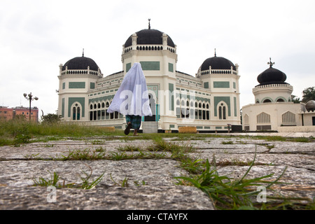 Pellegrino musulmano di fronte oft ha grande moschea di Medan, la capitale di Sumatra Utara provincia, isola di Sumatra, Indonesia, a sud-est Foto Stock