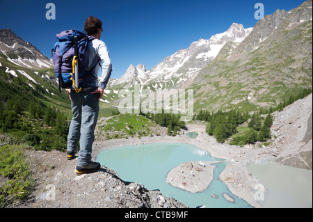 Escursionista maschio godendo la vista sul bellissimo paesaggio del lago Mige, Mont Blanc, Courmayeur, Italia Foto Stock
