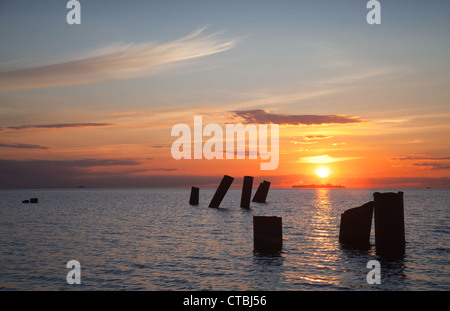 Parti della rottura di un molo sul mare al tramonto. Foto Stock