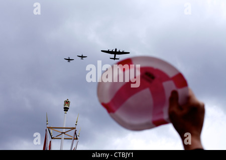 Battle of Britain sorvola, bombardiere Lancaster e due Spitfires, di fronte a un cappello a corona della bandiera di San Giorgio che viene sventolato per celebrare la seconda guerra mondiale Foto Stock