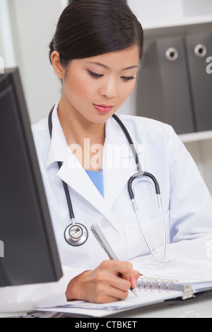 Un Cinese femmina asiatica medico iscritto in un ospedale di office Foto Stock