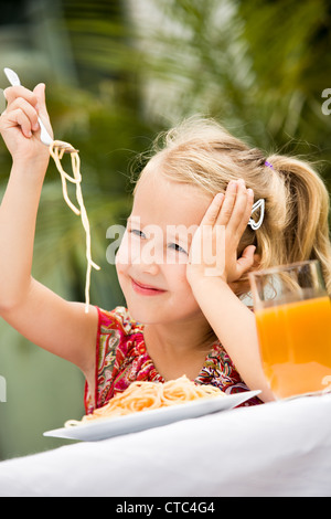 Ragazza Mangiare spaghetti in un giardino Foto Stock