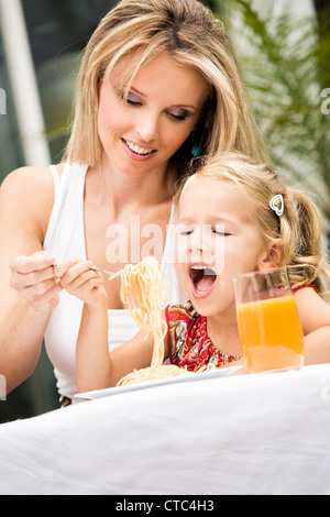 Ragazza Mangiare spaghetti in un giardino Foto Stock