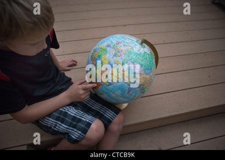 Dieci anni di vecchio ragazzo cerca per la Tanzania su un globo. Foto Stock