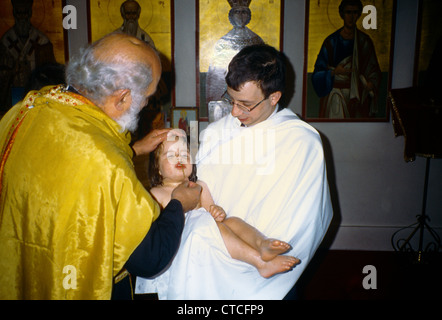 Kingston Surrey - greco-ortodossa sacerdote battesimo facendo segno di croce sulla nuova bambino battezzato padrino Ricezione di bambino Foto Stock