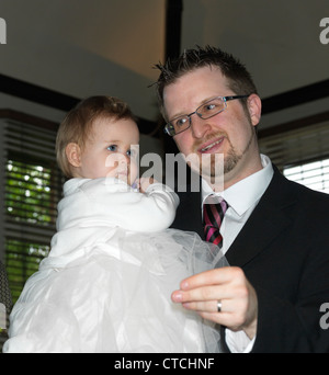 Padre Holding Baby girl dopo il Battesimo presso il ricevimento di battesimo Caterham sulla collina Surrey in Inghilterra Foto Stock