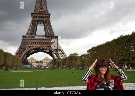 Un turista cinese pone a una foto davanti alla Torre Eiffel in Parc du Champ de Marc - Campo di Marte, Torre Eiffel a Parigi Foto Stock