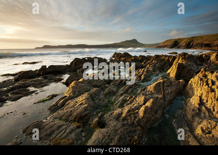 Tramonto su rocce sulla spiaggia Porthselau guardando verso St David's Head, Pembrokeshire, Galles Foto Stock