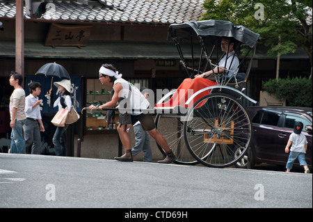 Turisti che cavalcano in risciò a Nara, Giappone. I pulller in risciò indossano stivali da lavoro jika-tabi a due punte Foto Stock