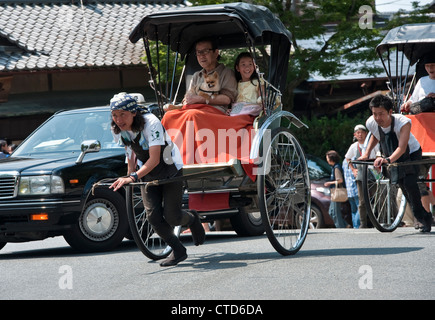 Turisti che cavalcano in risciò a Nara, Giappone. I pulller in risciò indossano stivali da lavoro jika-tabi a due punte Foto Stock