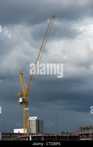 Grandi gru gialle contro un grigio scuro sky su un cantiere in Inghilterra. Foto Stock