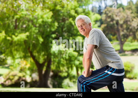 Uomo anziano che sta facendo il suo allungamento all'aperto Foto Stock