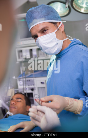 Medico chirurgo in possesso di una forbice durante un'operazione Foto Stock