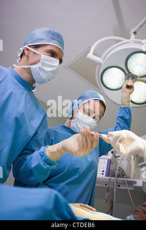 Il team di chirurgia di lavorare sotto le luci chirurgico Foto Stock