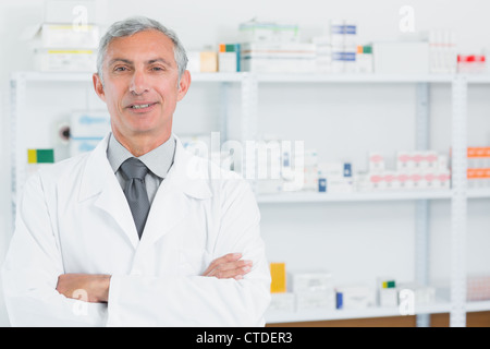 Il farmacista in piedi in una farmacia con le braccia incrociate Foto Stock