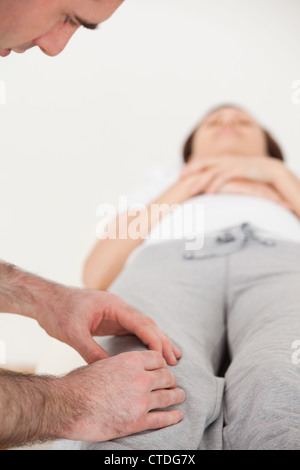 Donna sdraiata sulla schiena mentre un fisioterapista di massing suo ginocchio Foto Stock