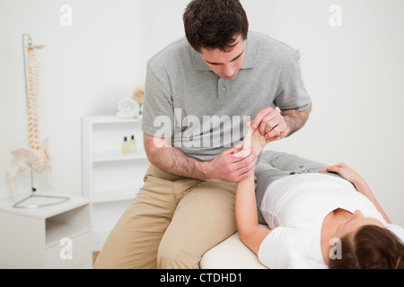 Fisioterapista cercando in corrispondenza del polso di un paziente Foto Stock