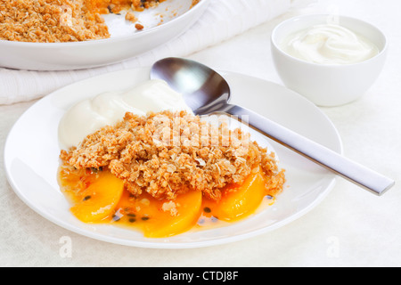 Un insolito frutto crumble con pesche e frutto della passione. Il crumble contiene farina integrale, lo zucchero di canna e di avena. Foto Stock