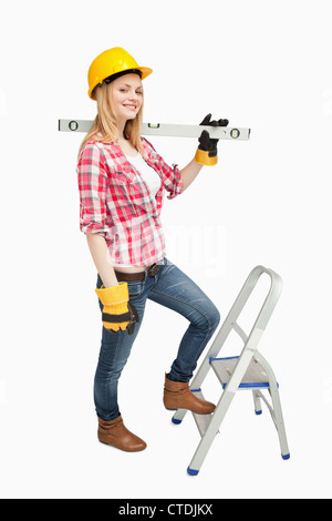 Donna che mantiene un livello di spirito accanto a una scala a pioli Foto Stock