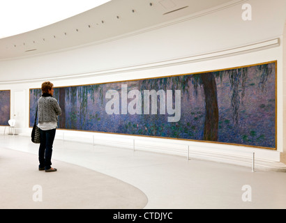 La donna la visualizzazione di uno degli otto "Nympheas' (le ninfee di Monet murales) al Musee de l'Orangerie, Parigi. Solo uso editoriale. Foto Stock