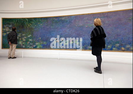 I visitatori la visualizzazione di uno degli otto ninfee murales alloggiata nel Musee de l'Orangerie di Parigi. Solo uso editoriale. Foto Stock