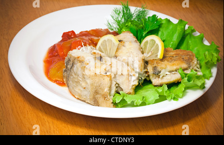 Eglefino fritto pesce con verdure e verdi su piastra bianca Foto Stock