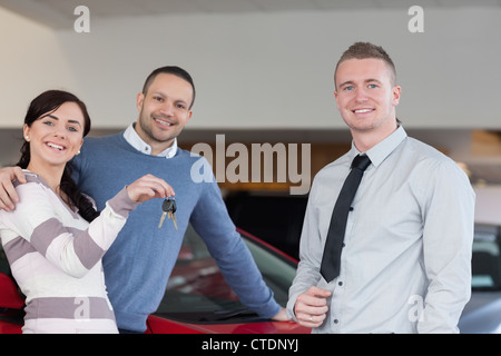 Venditore di dare le chiavi per un abbracciando giovane Foto Stock