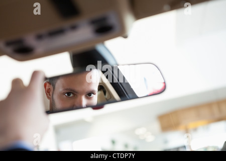 Uomo che guarda in un interno specchio auto Foto Stock