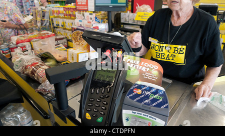 Un anziano impiegato femminile lavoratore anziano donna che lavorano dietro la cassa cassa Jesse & Kelly senza fronzoli supermercato Canada KATHY DEWITT Foto Stock