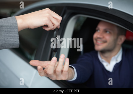 L'uomo riceve le chiavi dell'auto mentre è seduto nella sua auto Foto Stock