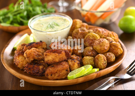 Panato calamari fritti pezzi con piccole patate al forno e tzatziki Foto Stock