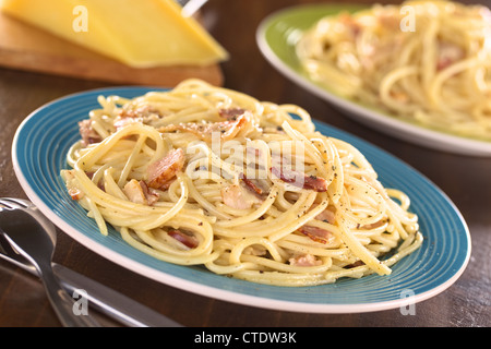 Spaghetti alla carbonara fatta con pancetta, uova, formaggio e pepe nero (fuoco selettivo, la messa a fuoco di un terzo nel pasto) Foto Stock