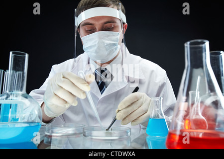 Uomo in uniforme medica studia campione nella scatola di Petri Foto Stock