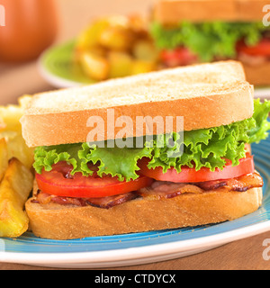 Freschi Fatti in casa BLT (pancetta lattuga e pomodoro) panino con patatine fritte sulla piastra blu Foto Stock