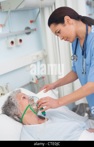 L'infermiera mettendo le maschere di ossigeno su un paziente Foto Stock
