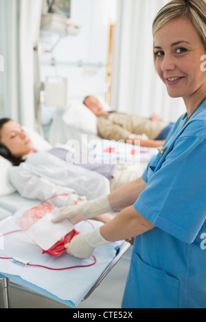 Un infermiere in possesso di una sacca di sangue Foto Stock