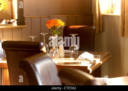 Ristorante impostazione tabella che mostra le sedie in pelle , occhiali e fiori Foto Stock