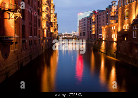 Magazzini illuminato e il canale nello storico quartiere Speicherstadt, Città Libera e Anseatica di Amburgo, Germania, Europa Foto Stock