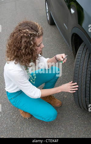 Giovani driver femmina pneumatico di controllo profondità su una vettura a ruote Foto Stock