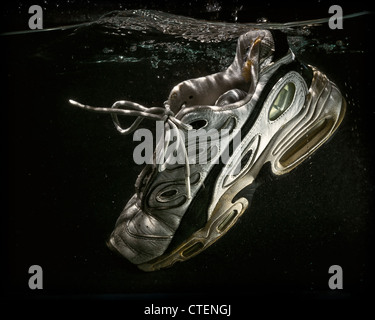 Un ben indossati e la vecchia scarpa da tennis galleggianti sommerso in acqua. Foto Stock