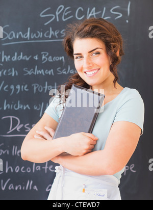Stati Uniti d'America, New Jersey, Jersey City, Ritratto di sorridente cameriera contro la lavagna con menu Foto Stock