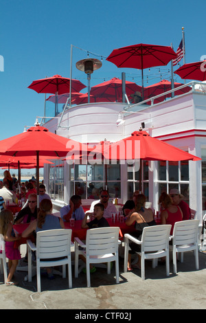 Gli amici e la famiglia di godere di un pasto in ombra di ombrelli a Ruby's ristorante sul molo di Balboa di Newport Beach in California Foto Stock