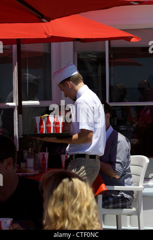 Cameriere che porta un vassoio di bevande al Ruby's ristorante sul molo di Balboa di Newport Beach in California Foto Stock