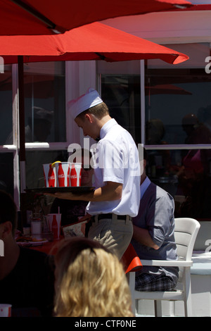 Cameriere che porta un vassoio di bevande al Ruby's ristorante sul molo di Balboa di Newport Beach in California Foto Stock