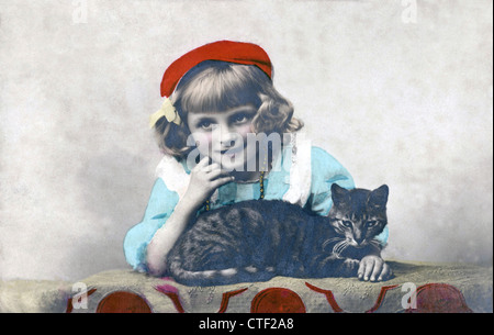 Giovane ragazza che indossa un berretto rosso con il suo gatto, 1906 vintage photo Cartolina. Foto Stock